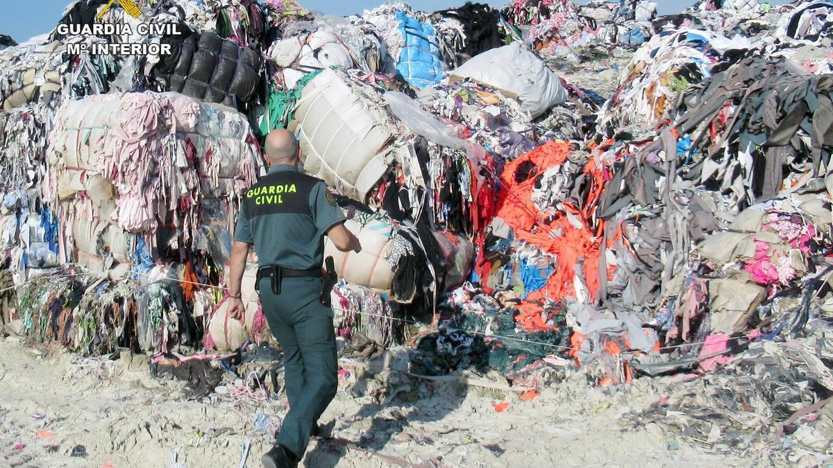 Un agente de la Guardia Civil, en el solar del  municipio molinense donde se hallaron 800  toneladas de residuos textiles.  G.C.
