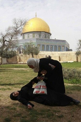 The Dome of the Rock is seen in the background as a Palestinian woman falls after a stun grenade was throw by Israeli policemen during clashes in Jerusalem's Old City