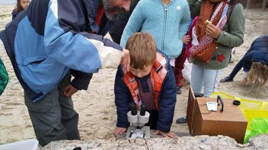 Los niños en la observación de los microplásticos en la playa. // Fdv