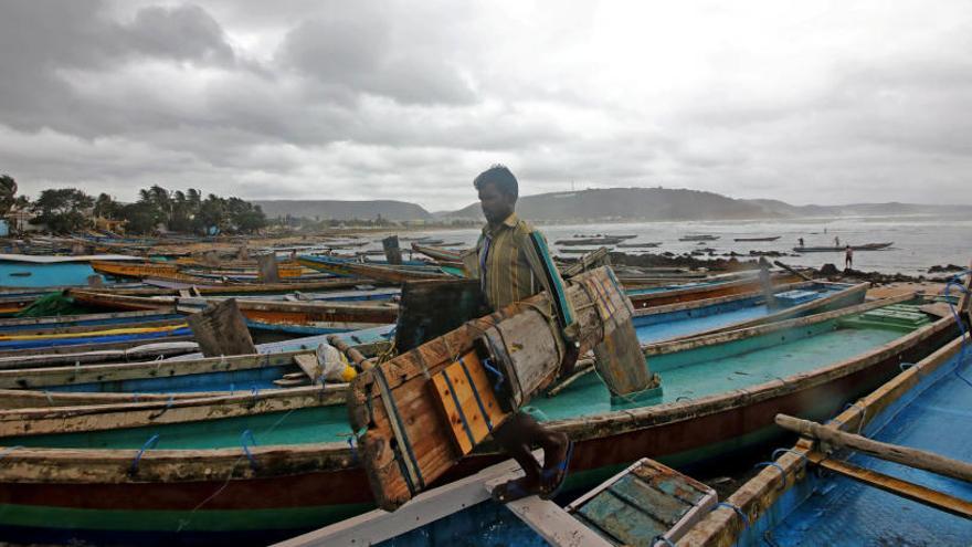 Un pescador junto a unos botes preparados para el tifón.