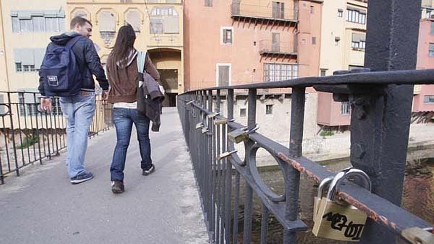 Dues persones caminen al costat d&#039;una desena de cadenats enganxats al pont d&#039;en Gómez, també conegut com el pont de la Princesa.