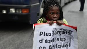 Una niña sujeta una pancarta con el lema Nunca más en esclavos en África en una protesta de migrantes en Grecia.