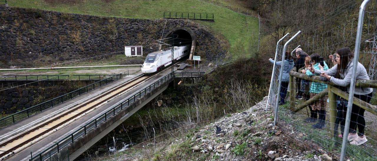 El tren inaugural sale de la boca del túnel de Los Pontones, en Lena, ante la expectación de los vecinos.