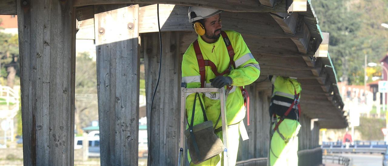 Operarios electricistas ponen luces en el puente de A Barca