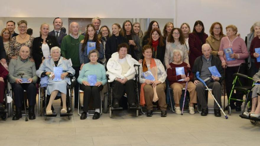 Los 17 mayores, protagonistas de sus propias historias, posan con sus libros y los autores voluntarios en la Fundación María José Jove. |  LCO
