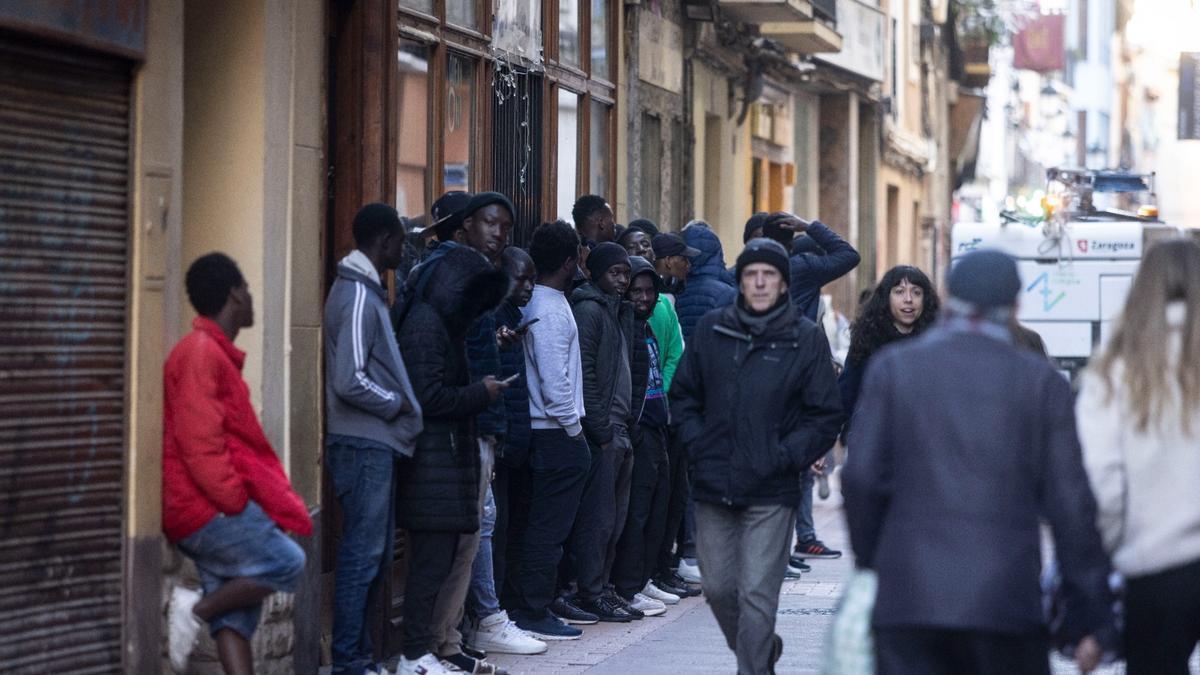 Un grupo de migrantes frente al hotel en el que se alojan en Zaragoza al que le ha sido rebajada la licencia.