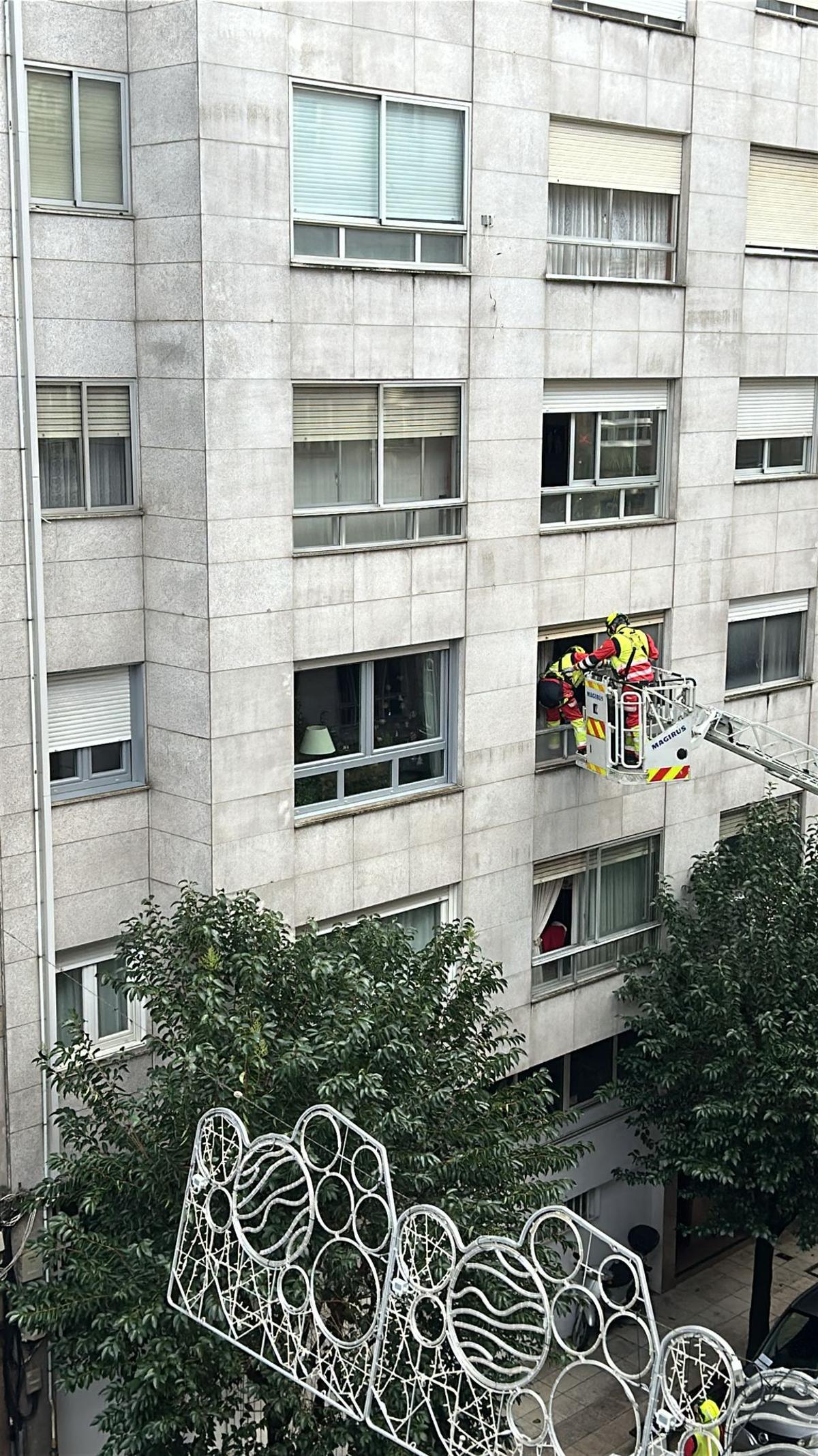 Los bomberos entrando por la ventana en el domicilio de la calle Ecuador.