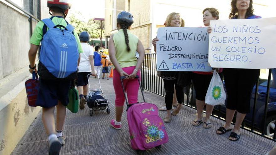 Alumnos de un colegio de infantil y primaria de Antequera (Málaga), a su llegada hoy, martes 12 de junio de 2012, a clase con cascos protectores en la cabeza como protesta por los desprendimientos de cornisas en el centro, apoyados por numerosos padres y algunos profesores.