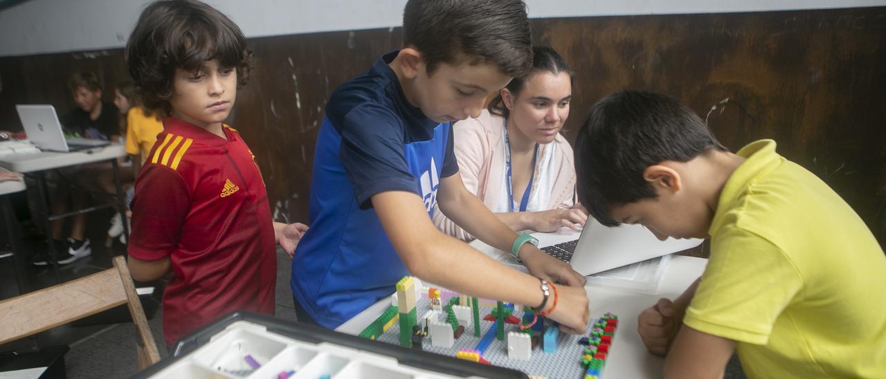 Tres de los niños participantes en el taller, con la monitora del mismo.