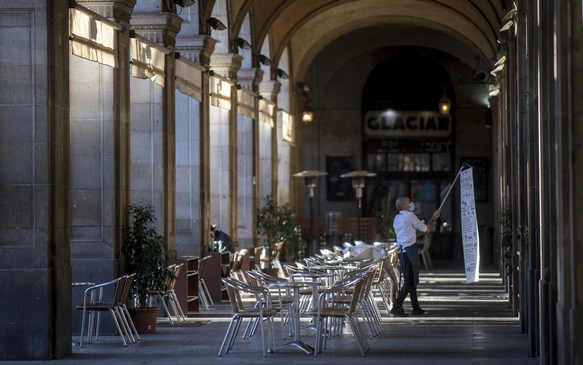 Un camarero cuelga un cartel junto a una terraza de la plaza Reial, en Barcelona, en diciembre de 2020.