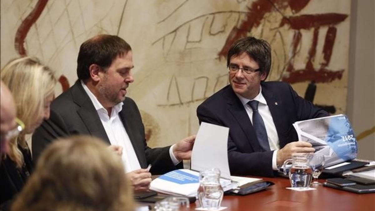 El vicepresidente del Govern, Oriol Junqueras, y el 'president', Carles Puigdemont, con el proyecto de ley de los presupuestos de la Generalitat para el 2017 en la reunión del Consell Executiu, este martes.