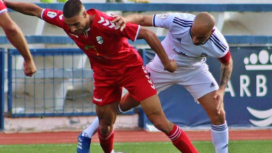 Ismael Fagir -de rojo- intenta controlar el balón ante la presión de un jugador del Marbella en el partido de ayer.