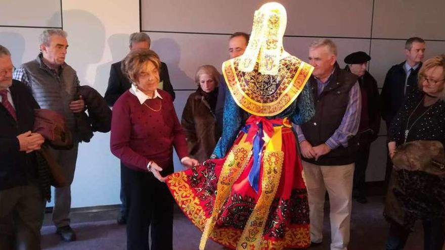 Ana Crespo, rodeada de los invitados a la inauguración de la exposición, muestra los detalles de uno de los vestidos expuestos en Valbusenda.