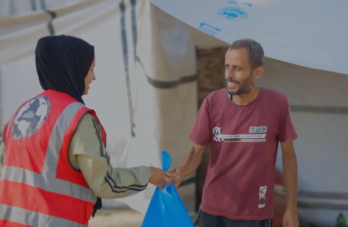 Una voluntario entrega los víveres a un padre de familia palestino.