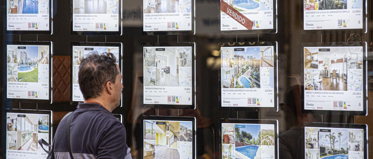 Un hombre observa la oferta de pisos en venta en una iinmobiliaria valenciana.