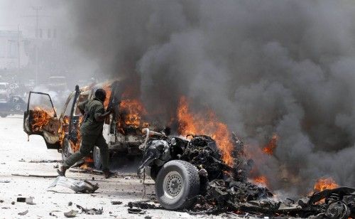 A policeman runs through burning vehicles at the scene of an explosion near the presidential palace in Somalia's capital Mogadishu