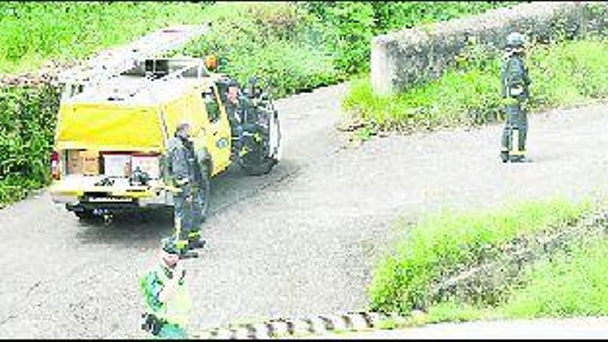 Bomberos y Guardia Civil, ayer, en las inmediaciones de la casa, en La Reguera, durante el corte de la carretera.