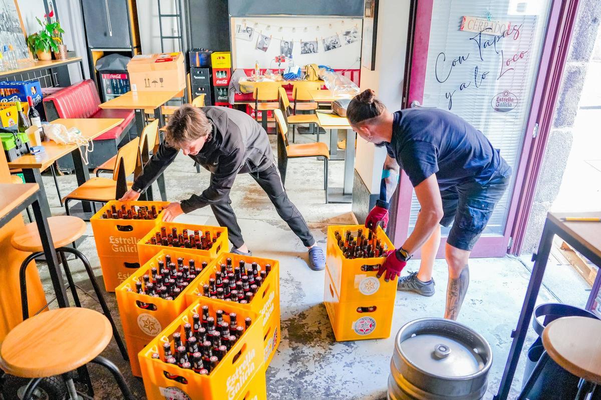 Trabajadores de una distribuidora cargando botellas y barriles.