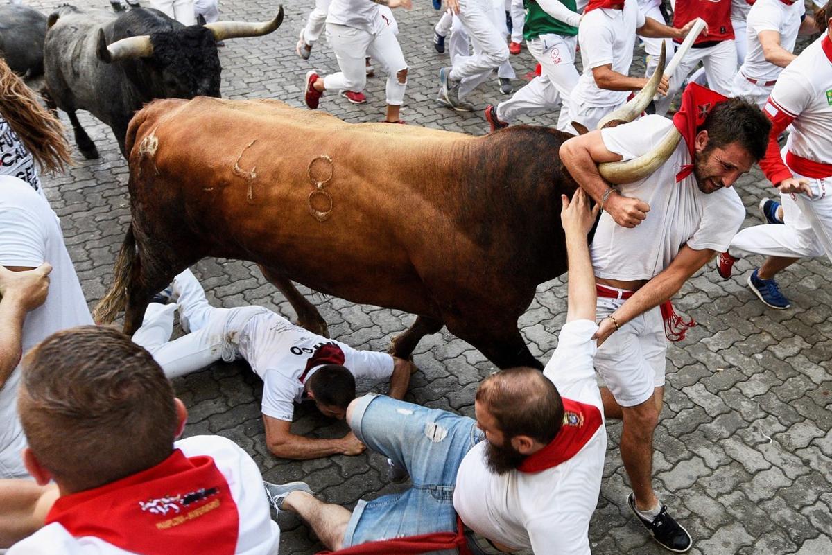 GRAF131. PAMPLONA, 14/07/2018.- Un toro de la ganadería sevillana de Miura arrastra a un mozo a su paso en el tramo de entrada al callejón de la Plaza durante el octavo y último encierro de los Sanfermines 2018, el más rápido de las fiestas con 2 minutos y 12 segundos de duración, en el que, según el primer parte médico, no hay heridos por asta. EFE/Daniel Fernández GRAF131. PAMPLONA, 14/07/2018.- Un toro de la ganadería sevillana de Miura arrastra a un mozo a su paso en el tramo de entrada al callejón de la Plaza durante el octavo y último encierro de los Sanfermines 2018, el más rápido de las fiestas con 2 minutos y 12 segundos de duración, en el que, según el primer parte médico, no hay heridos por asta. EFE/Daniel Fernández
