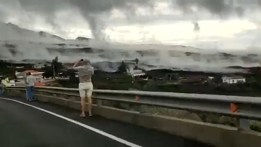 Varios curiosos observan la impactante imagen del vapor que sale de las coladas del volcán de La Palma.