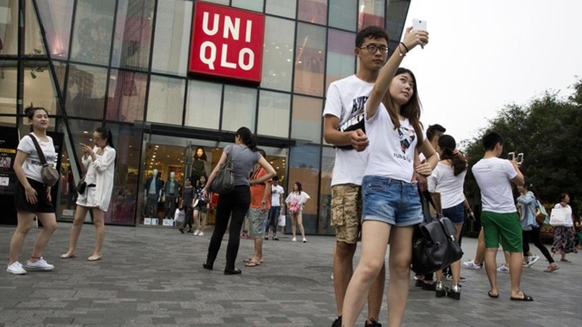Una pareja de jóvenes se hacen un seli frente a la cadena de ropa Uniqlo, en Pekín, este jueves.