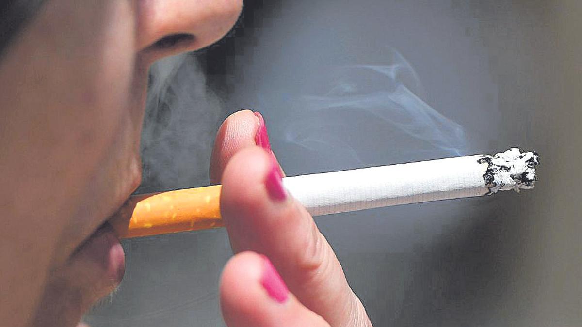 Una mujer fumando un cigarillo que desprende humo a su alrededo