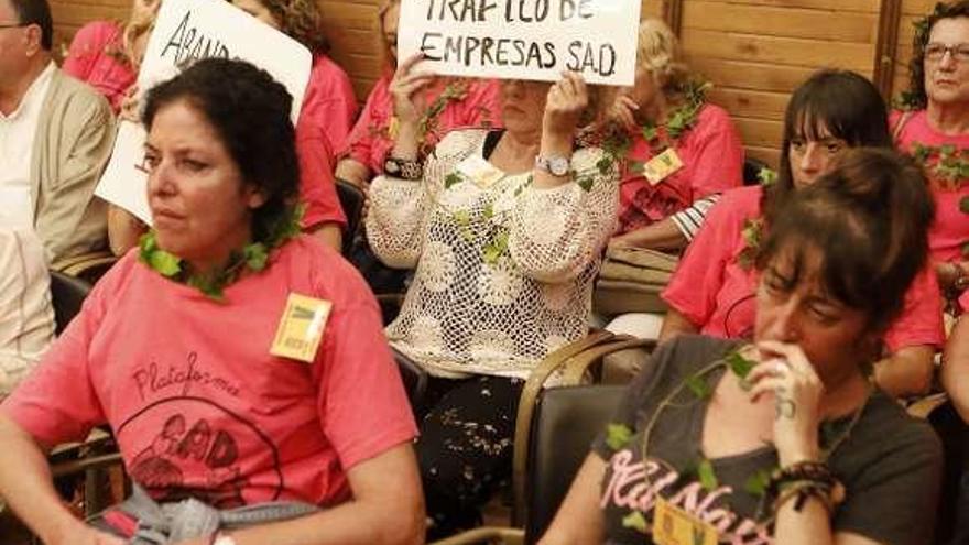 Trabajadoras del servicio de ayuda a domicilio, con enredaderas en sus cuellos, durante una protesta en el Pleno.