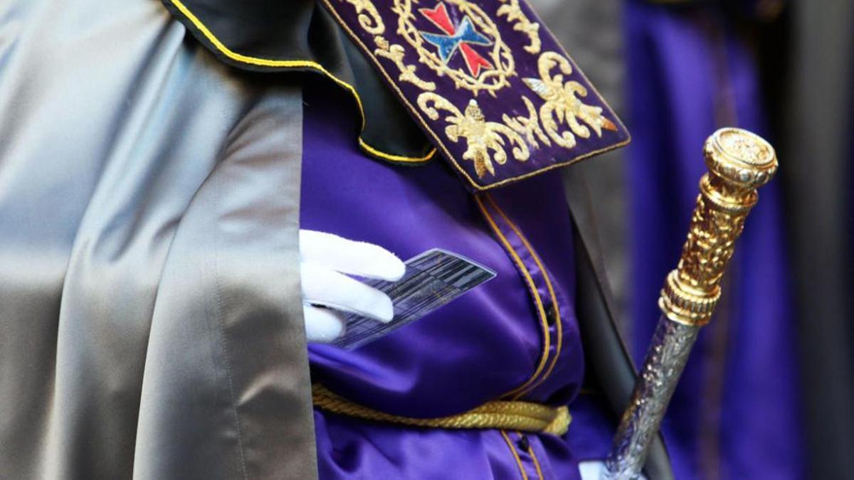 Un nazareno del Rescate consulta el cuadrante con los horarios.