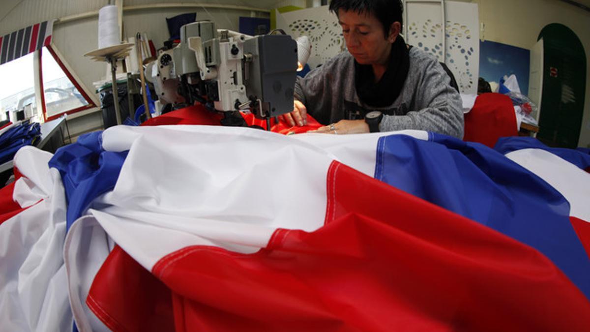 Una trabajadora de la empresa Doublet cose una bandera francesa, ayer en Lille.