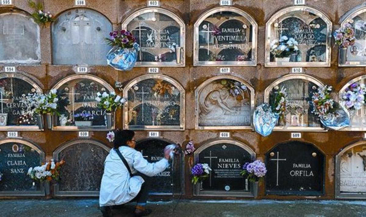 Una mujer limpia un nicho en el cementerio del Poblenou.