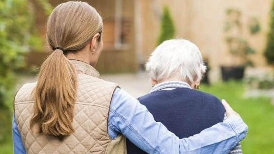 Una mujer ayuda a una anciana a desplazarse.