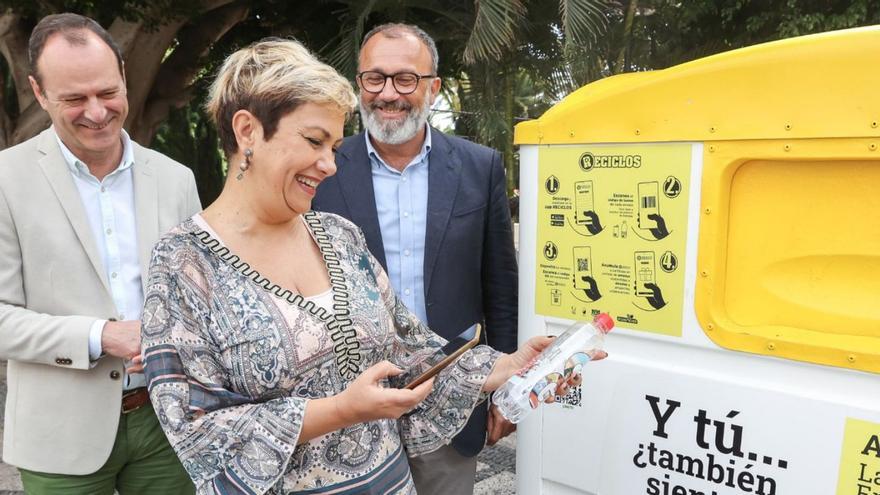 Ana Hernández, entre Óscar Hernández y Francisco García, ayer, con un envase ante el contenedor amarillo. | | E.E.