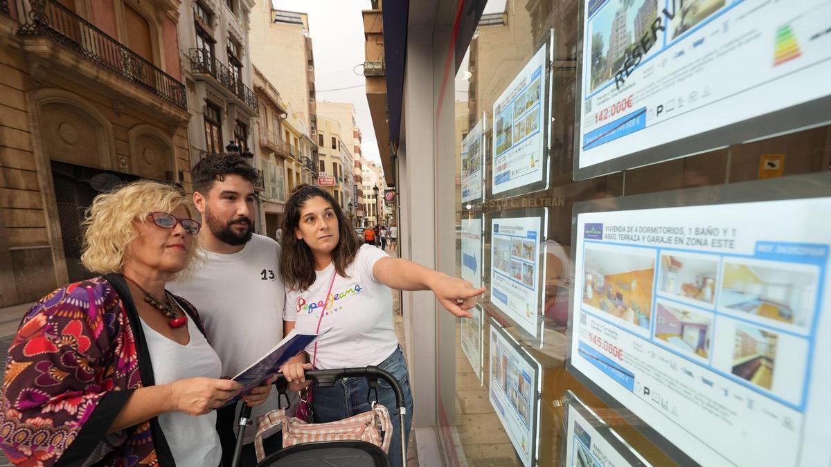 Unos jóvenes observan las ofertas de pisos en una inmobiliaria en una imagen de archivo.