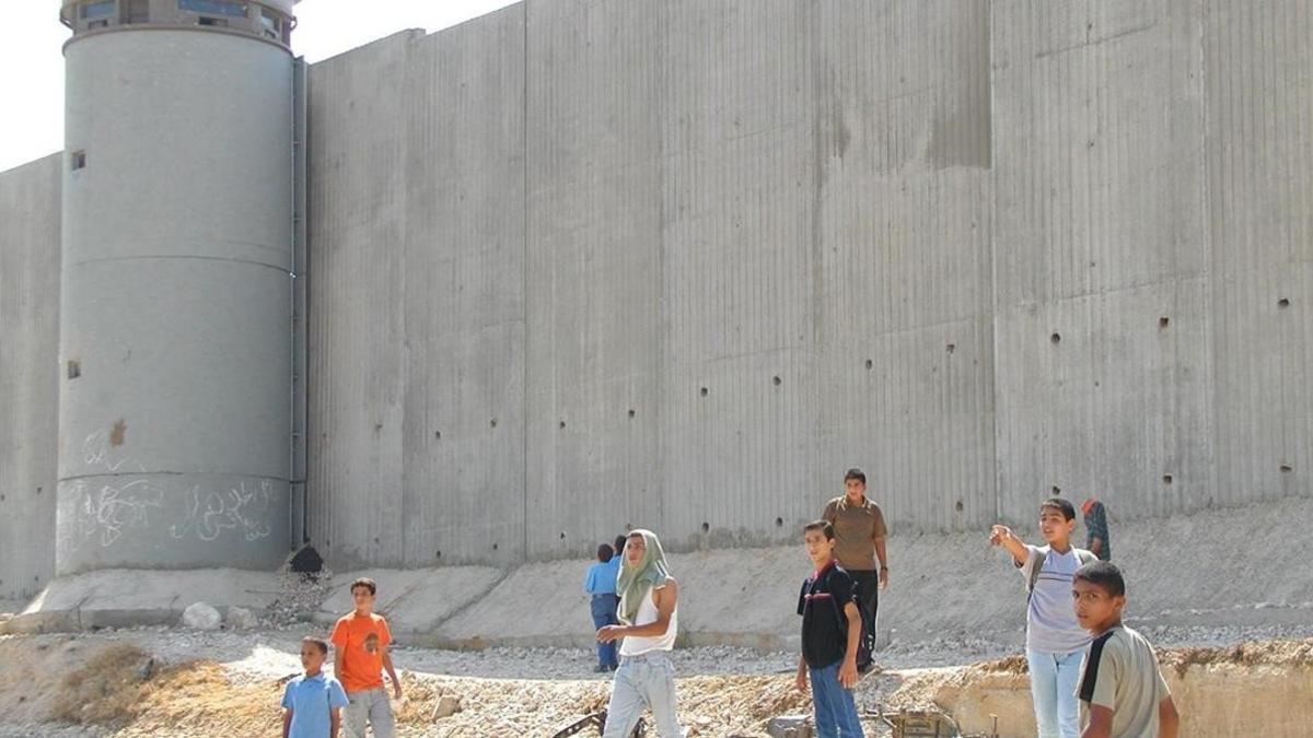 Niños palestinos de camino a la escuela, junto al muro construido por Israel cerca de Qalqilya (Cisjordania), el 22 de septiembre del 2003.