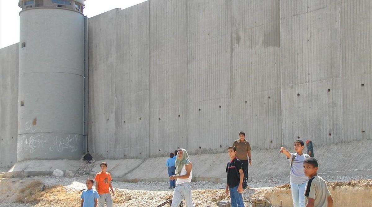 Niños palestinos de camino a la escuela, junto al muro construido por Israel cerca de Qalqilya (Cisjordania).