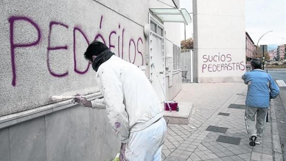 Un operario borra pintadas contra los acusados en la parroquia de Román Martínez.