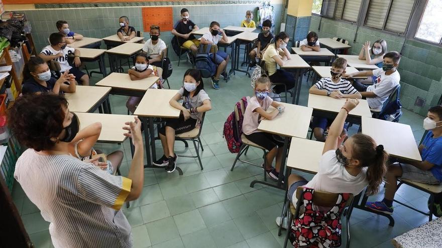 Alumnos de Primaria en clase con una docente y todos con las mascarillas puestas.