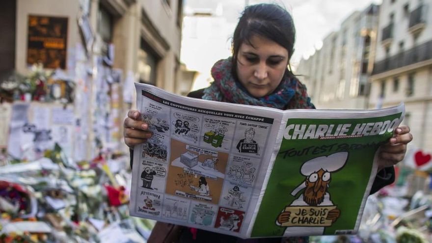 Una mujer sostiene una publicación del semanario satírico Charlie Hebdo.