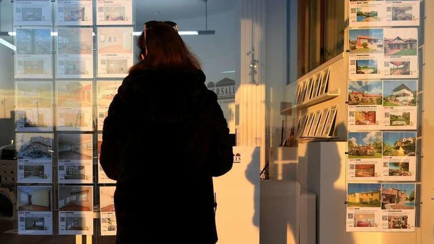 Una mujer observa el escaparate de una inmobiliaria.