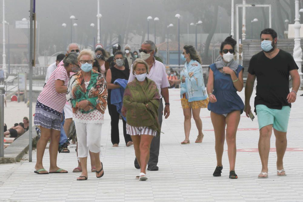 Los vigueses estrenan  las mascarillas obligatorias en Galicia en la playa y en medio de la niebla