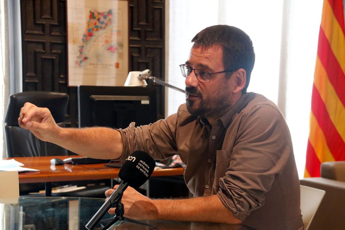 L'alcalde de Girona, Lluc Salellas, i, al fons, el mapa dels Països Catalans que té al despatx d'alcaldia