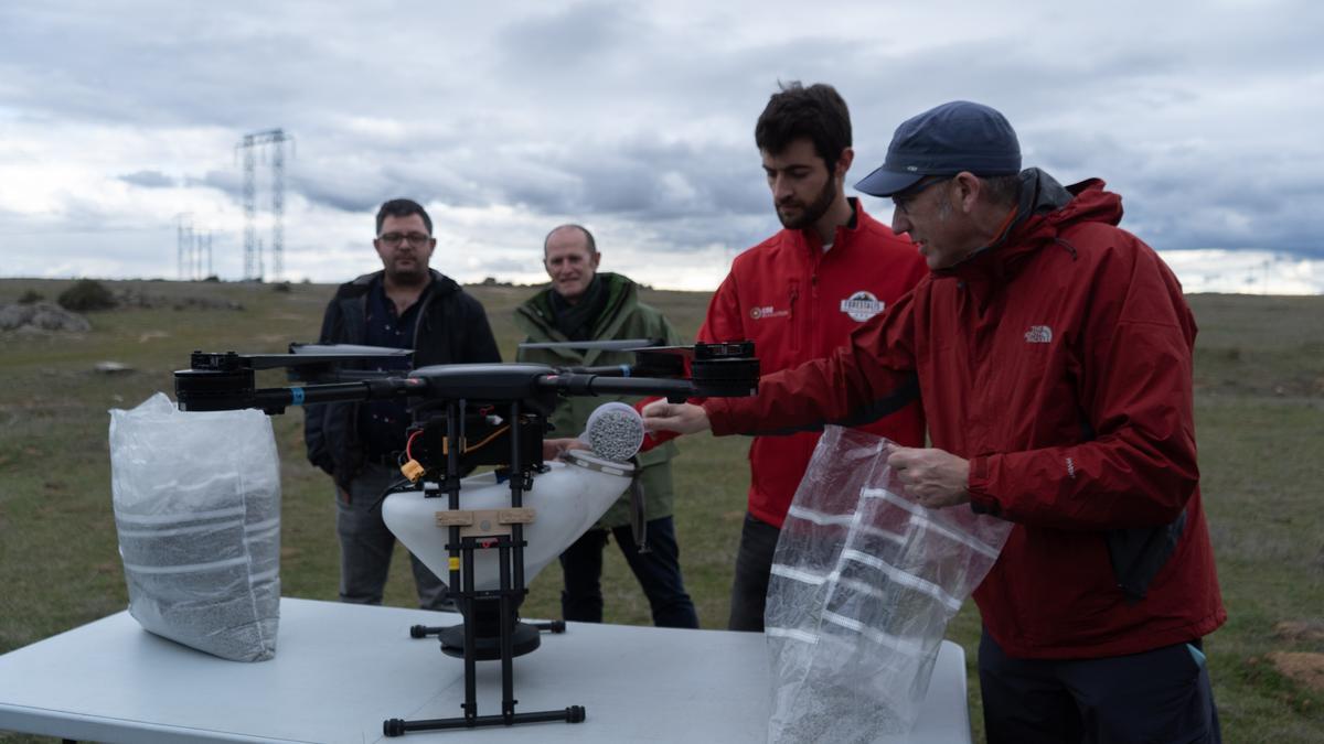 Los operarios llenan de semillas el dron.