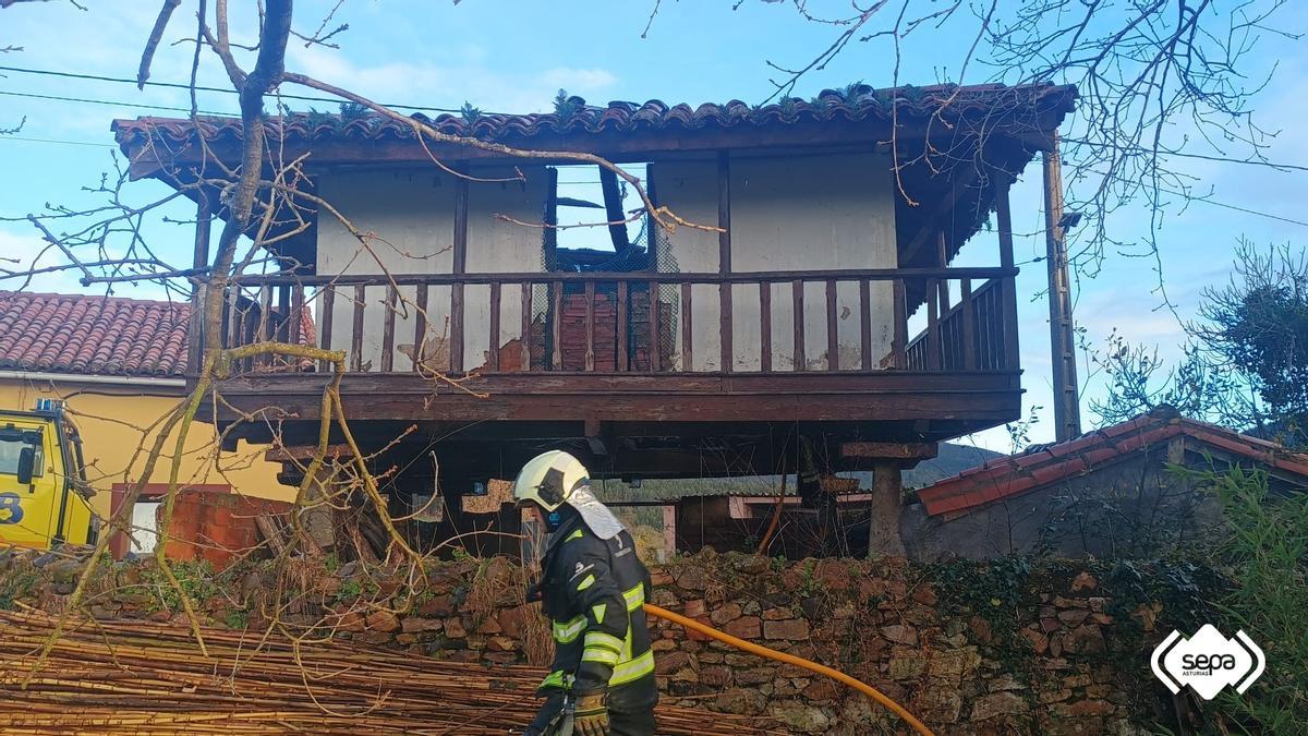 Un bombero trabajando en la extinción de las llamas en el hórreo.