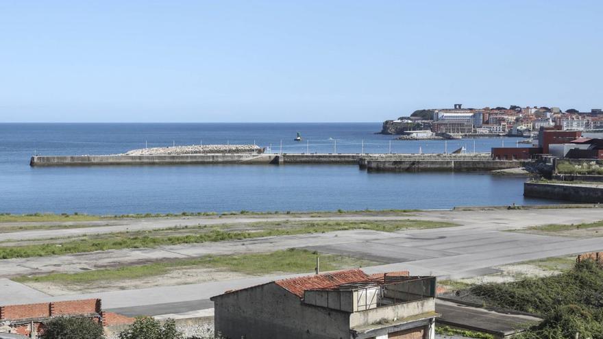 En primer término, parte de los terrenos de Naval Gijón, con el acuario y el espigón que separa su dársena del paseo de Vicente Álvarez Areces en el centro de la imagen y el Cerro con el "Elogio del Horizonte" al fondo.