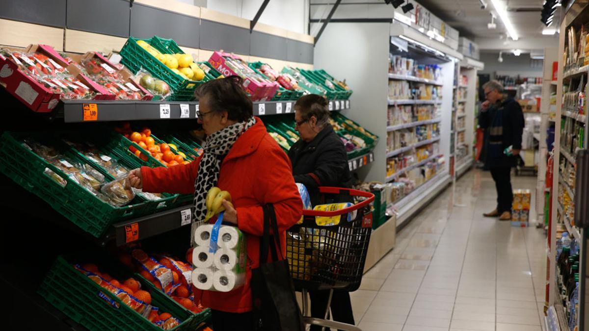 Varias personas realizan la compra en un supermercado.