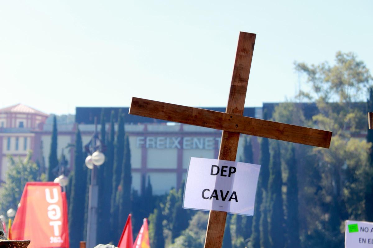 Una cruz con el cartel DEP Cava con Freixenet al fondo durante la manifestació Una cruz con el cartel DEP Cava con Freixenet al fondo durante la manifestació