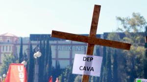 Una cruz con el cartel DEP Cava con Freixenet al fondo durante la manifestació