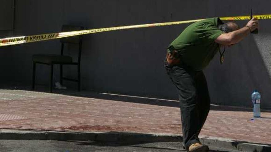 Un agente de la UDEV pasa junto a los restos de sangre de los heridos en el tiroteo.