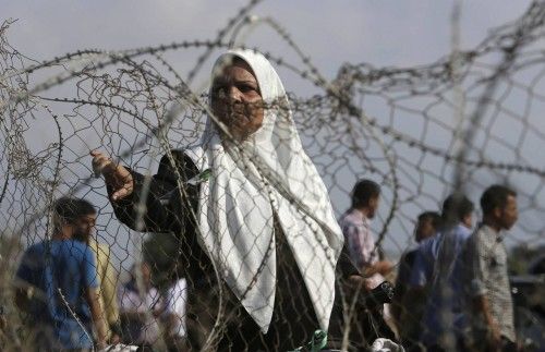 Palestinian woman hoping to cross into Egypt stands behind fence as she waits at Rafah crossing between Egypt and southern Gaza Strip