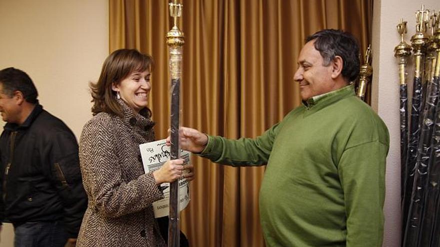 Una mujer recoge con satisfacción la vara con la que procesionará el día de Viernes Santo.